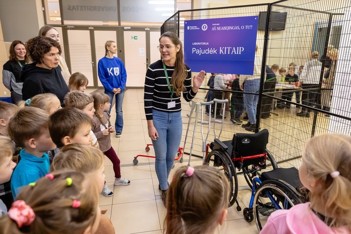Techninės pagalbos priemonių centro atstovė (viduryje) pasakoja parodos dalyviams apie judėjimo techninės pagalbos priemones.