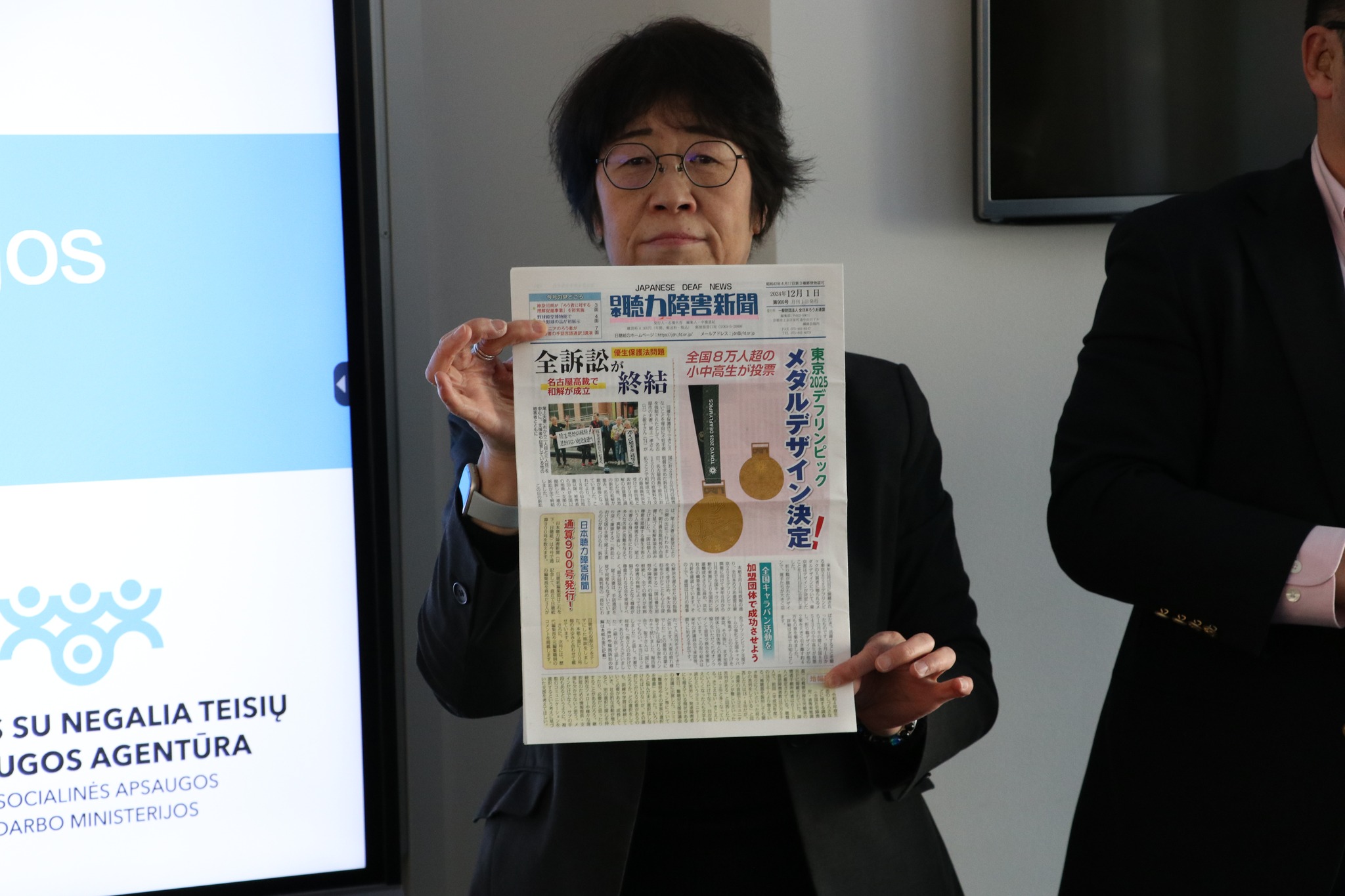 Japonijos atstovė laiko laikraštį, kuriame japonų kalba parašyta apie Arūną